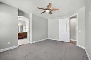 Unfurnished bedroom featuring light carpet, ceiling fan, arched walkways, ensuite bath, and a textured ceiling