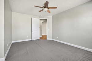 Unfurnished bedroom featuring carpet floors, ceiling fan, arched walkways, and a textured ceiling