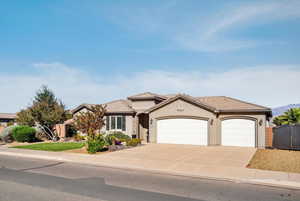 View of front of home featuring stucco siding, driveway, an attached garage, a gate, and a tile roof