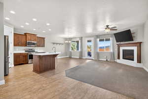 Kitchen featuring appliances with stainless steel finishes, a chandelier, a center island with sink, hanging light fixtures, and a breakfast bar