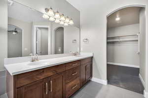 Full bathroom featuring a spacious closet, dark tile patterned flooring, double vanity, and ceiling fan