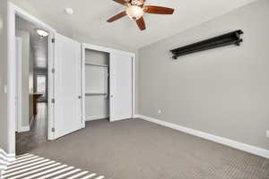 Unfurnished bedroom with carpet, a closet, and a ceiling fan