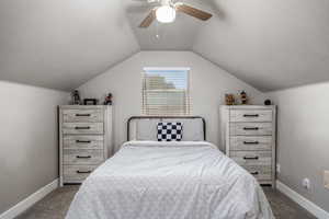 Carpeted bedroom with vaulted ceiling, ceiling fan, and a textured ceiling