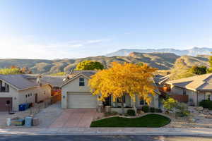 View of front of house with stucco siding, a mountain view, concrete driveway, a garage, and covered porch