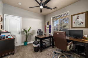 Carpeted office space featuring a ceiling fan and baseboards