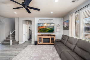 Living area featuring wood finished floors, ceiling fan, recessed lighting, stairway, and arched walkways