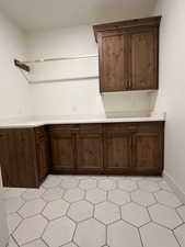 Kitchen with dark brown cabinets, light floors, and light stone counters