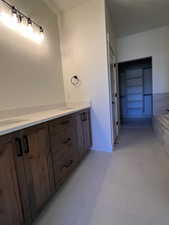 Bathroom with double vanity, tiled bath, and light tile patterned floors