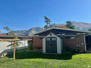 Rear view of house featuring a mountain view, brick siding, and a storage shed