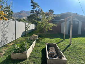 Fenced backyard with a storage shed, a garden, and a mountain view