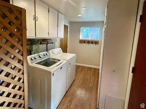 Laundry room with light wood finished floors, cabinet space, washer and dryer, and recessed lighting