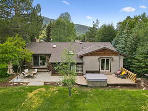 Back of property with a yard, a deck with mountain view, a chimney, stucco siding, and french doors