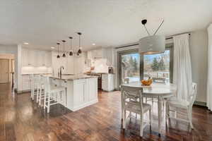 Dining area with dark wood-style floors, a textured ceiling, and recessed lighting