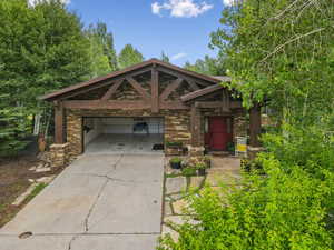 View of front of home with driveway and stone siding
