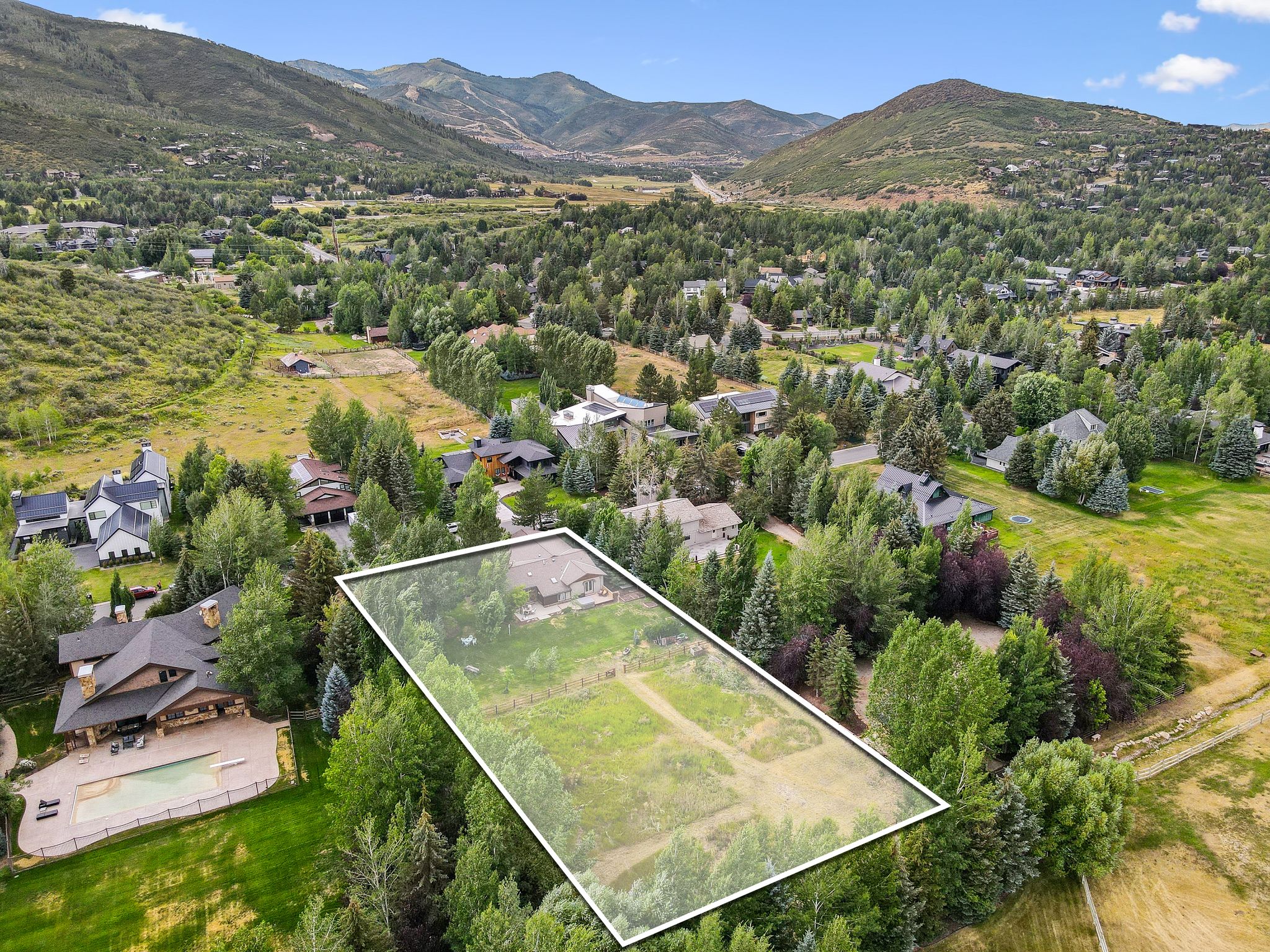 Aerial view of residential area with a mountain backdrop and property parcel outlined