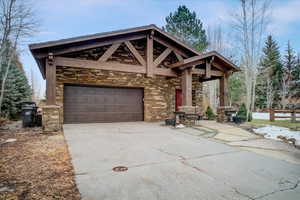 View of front facade featuring concrete driveway, stone siding, and covered porch