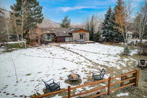 Snow covered rear of property with a patio area and a hot tub