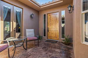 Entrance to property with stucco siding and a patio