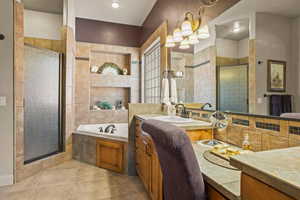 Bathroom featuring a garden tub, vanity, a shower stall, tile walls, and light tile patterned flooring