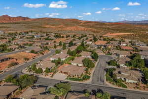 Aerial view of property and surrounding area featuring a mountain backdrop and nearby suburban area