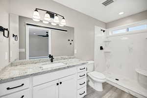 Full bath with vanity, light wood finished floors, a marble finish shower, recessed lighting, and a ceiling fan