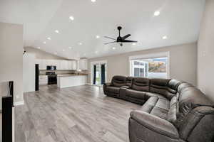 Living room with light wood finished floors, recessed lighting, lofted ceiling, and ceiling fan