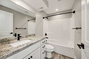 Bathroom featuring bathing tub / shower combination, light wood-type flooring, vanity, and recessed lighting