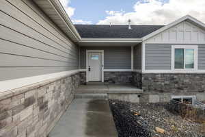 Entrance to property with stone siding and roof with shingles