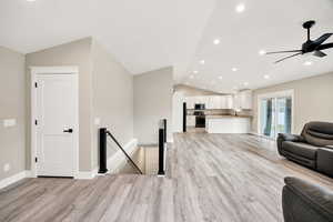 Living area featuring vaulted ceiling, recessed lighting, light wood-style flooring, and a ceiling fan