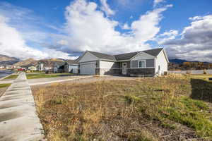 View of front of house with stone siding, a mountain view, board and batten siding, driveway, and roof with shingles
