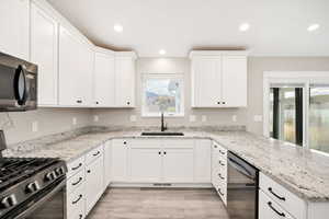 Kitchen with gas stove, recessed lighting, white cabinets, light stone counters, and dishwasher