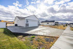 View of side of property featuring concrete driveway, stone siding, board and batten siding, and an attached garage