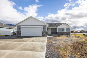 Craftsman inspired home featuring stone siding, board and batten siding, driveway, and a garage