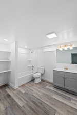 Full bathroom featuring vanity, washtub / shower combination, light wood-style floors, and a textured ceiling