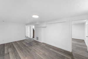 Finished basement featuring wood finished floors, stairway, and a textured ceiling