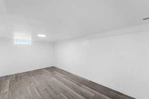 Basement with wood finished floors and a textured ceiling
