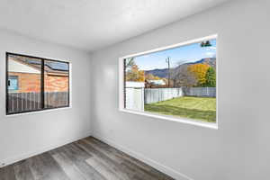 Spare room with a mountain view, a textured ceiling, and wood finished floors