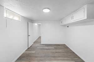 Finished basement featuring a textured ceiling and light wood-style floors
