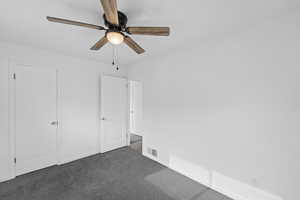 Unfurnished bedroom with dark colored carpet and a ceiling fan
