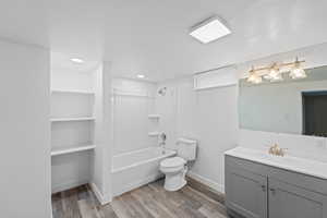 Bathroom with vanity, tub / shower combination, light wood-style flooring, and a closet