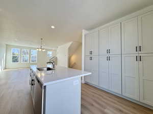 Kitchen with pendant lighting, light wood-style floors, white cabinetry, recessed lighting, and light stone counters