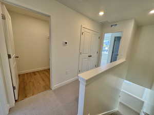 Hall featuring light carpet, recessed lighting, and an upstairs landing