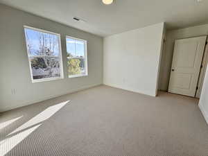 Unfurnished room with light colored carpet and a textured ceiling