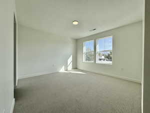 Carpeted empty room with a textured ceiling and baseboards