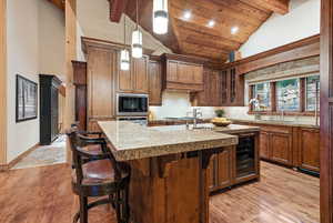 Kitchen featuring backsplash, a breakfast bar area, light wood-type flooring, a center island with sink, and glass insert cabinets