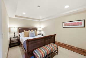Carpeted bedroom with recessed lighting, a baseboard radiator, and a raised ceiling