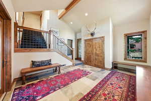 Foyer with beam ceiling, high vaulted ceiling, stairway, and recessed lighting
