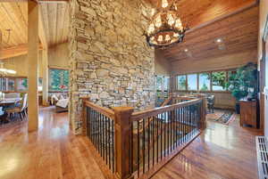 Hallway featuring a chandelier, high vaulted ceiling, an upstairs landing, wood ceiling, and plenty of natural light