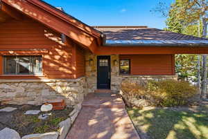 Entrance to property with stone siding and a shingled roof