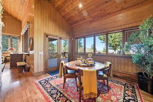 Dining room featuring light wood-style floors, healthy amount of natural light, high vaulted ceiling, wood ceiling, and french doors